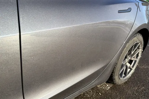 Pelēka automa&scaron;īna ar tīrāmām sānu durvīm, saules apgaismota, skats no sāniem.