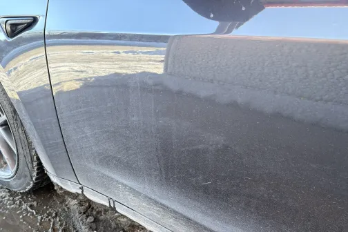 Netīras automa&scaron;īnas sānu durvis ar redzamām putekļu līnijām.