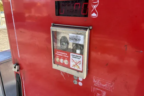 Sarkans automazgātuves automāts ar monētu &scaron;ķirbu un displeju.