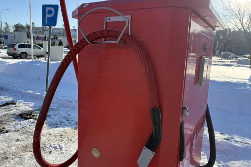 Sarkans putekļu sūcējs auto mazgātavā, fonā sniegs.