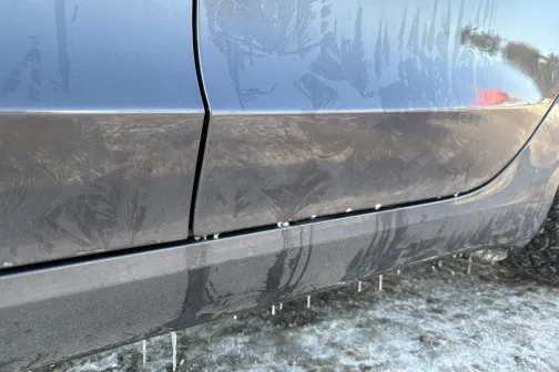 Netīra automa&scaron;īnas sānu mala ar sāls un dubļu pēdām sniegotā vidē.