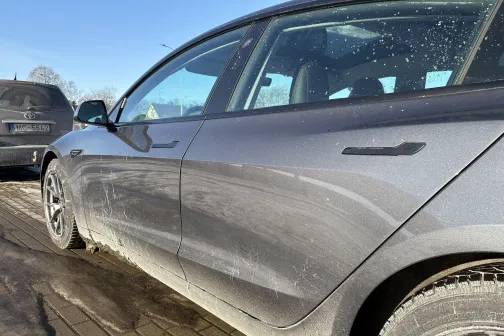 Netīra pelēka automa&scaron;īna stāvvietā, saulaina diena.