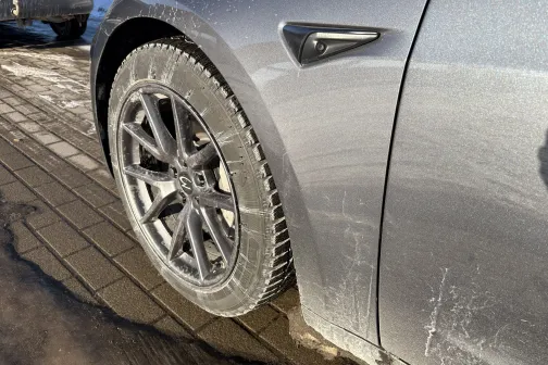 Netīra pelēka automa&scaron;īna ar ziemas riepām saulainā ziemas dienā.