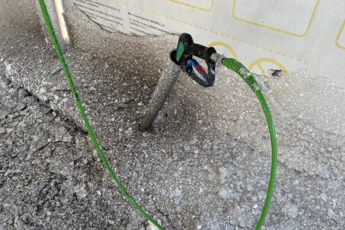 Zaļa &scaron;ļūtene pievienota pie ūdens krāna netīrā vidē.