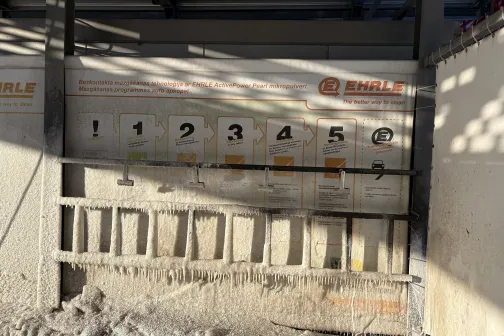 Mazgātavas siena ar numurētām instrukcijām un paklāju turētāju.