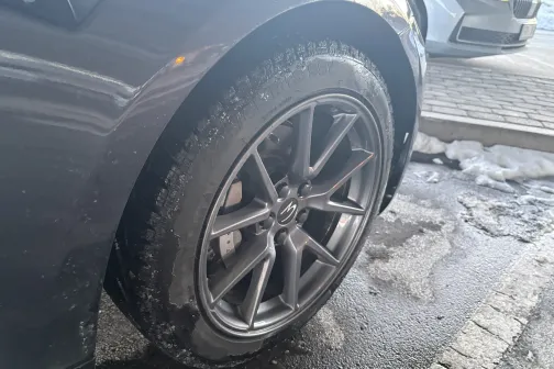 Automobiļa riteņa tuvplāns pie netīras automazgātuves grīdas.