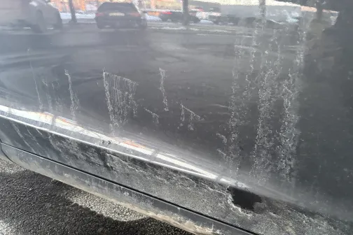 Netīra automa&scaron;īnas sānu virsma ar sāls un dubļu pēdām.