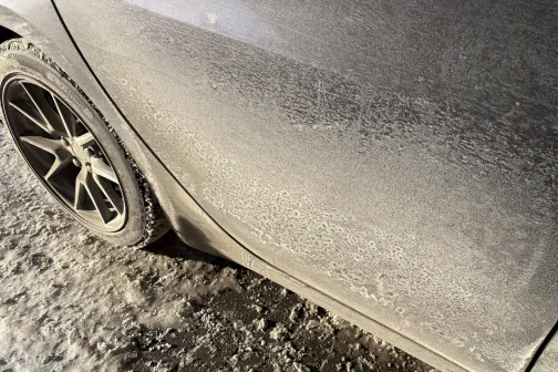 Putekļains auto sāns un ritenis saulainā gaismā.