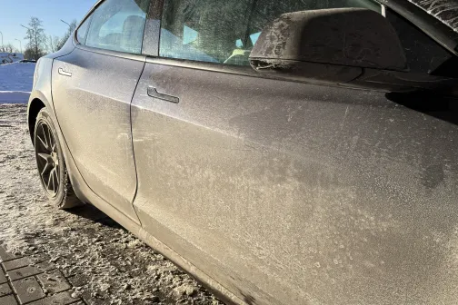 Netīrs automobilis saulainā ziemas dienā.