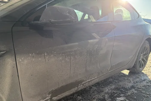 Netīrs auto sāns ar ceļa sāls traipiem, saulaina diena.