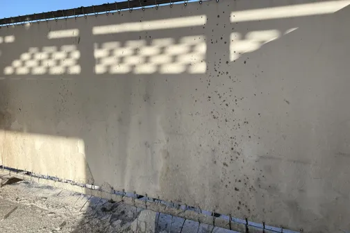 Ēnas uz sienas zem zilām debesīm.