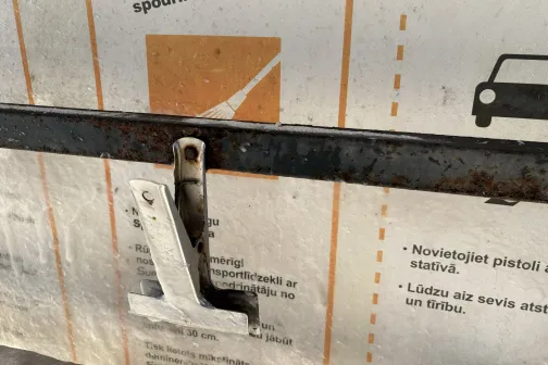 Metāla sviras mehānisms pie sienas ar instrukcijām un auto siluetu.