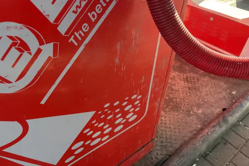 Sarkanā putekļsūcēja &scaron;ļūtene pie automazgātavas ierīces.