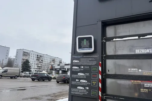 Auto mazgātava ar elektronisku ekrānu un blakus eso&scaron;ām ēkām.