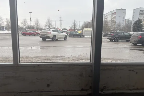 Skats uz ielu ar automa&scaron;īnām no loga, pelēka diena.