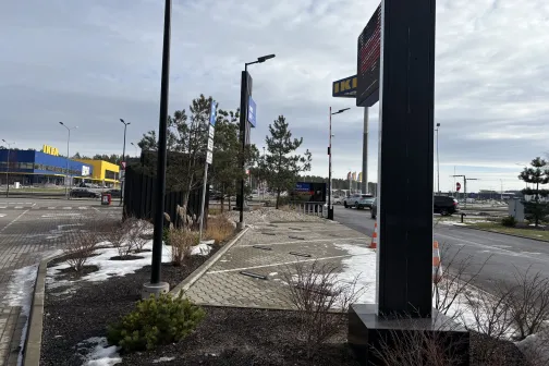 Āra autostāvvieta pie pilsētas centra, nojumē daži sniega plankumi.