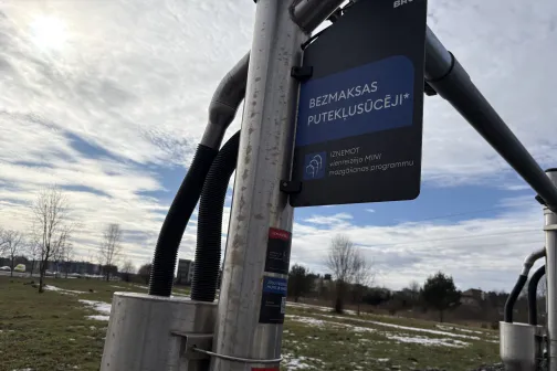 Metāla caurules ar norādi auto mazgā&scaron;anas stacijā, fonā zāliens un koki.