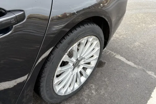 Melnas automa&scaron;īnas aizmugurējais ritenis ar sudraba disku uz asfalta.