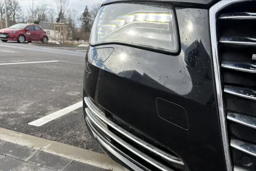 Auto priek&scaron;ējā luktura tuvplāns stāvvietā.