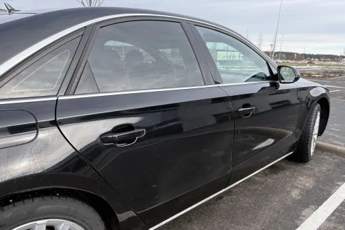 Melns sedans stāvvietā, skaidra debess.