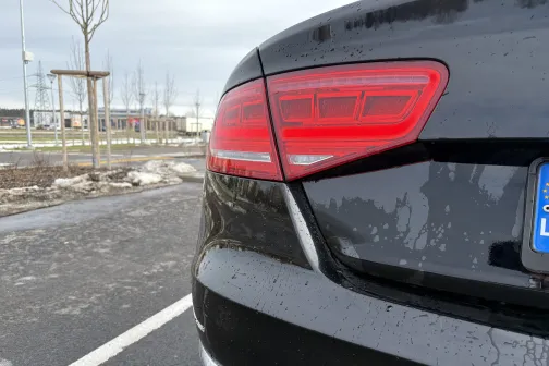 Melna automa&scaron;īna ar sarkanām aizmugurējām gaismām, stāv laukā.