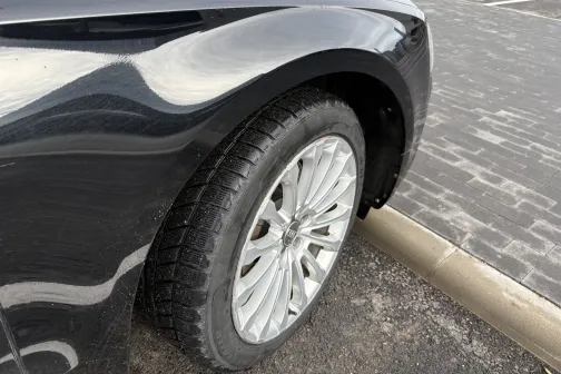 Melnas automa&scaron;īnas priek&scaron;ējais ritenis uz stāvvietas seguma.