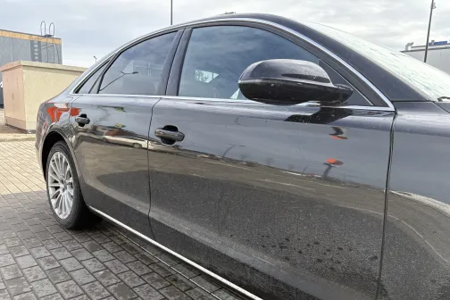 Melnas automa&scaron;īnas sānskats ar slapjiem dubļiem uz durvīm.