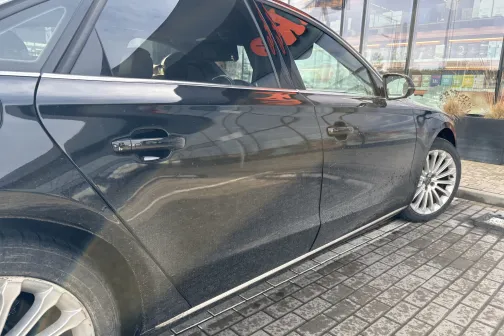 Melnas automa&scaron;īnas kreisā puse uz bruģa pie ēkas.