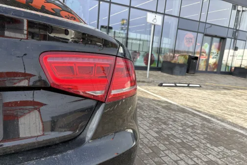 Melnas automa&scaron;īnas aizmugure pie auto mazgātuves ēkas.