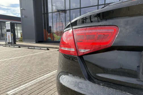 Melnas automa&scaron;īnas aizmugure stāvlaukumā pie ēkas.