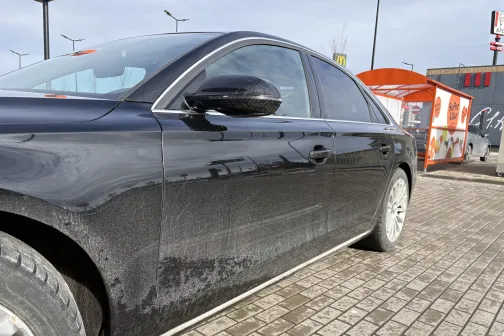 Netīra melna automa&scaron;īna stāv stāvlaukumā pie automazgātavas.