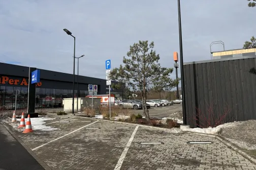 Automa&scaron;īnu stāvlaukums pie ēkas ar zilo debesu fona.