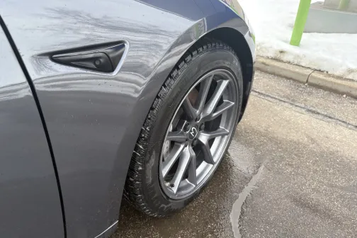 Pelēkas automa&scaron;īnas priek&scaron;ējais ritenis mitrā ielā.