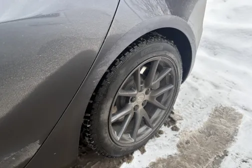 Pelēkas automa&scaron;īnas aizmugurējais ritenis, sniegā.