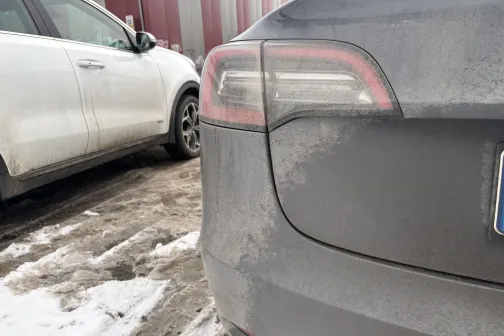 Divas netīras automa&scaron;īnas sniegotā stāvlaukumā.