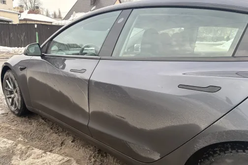 Netīrs pelēks sedans uz sniegaina ceļa.