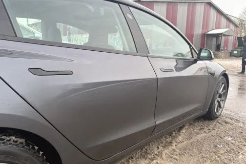 Pelēks automobilis pie automazgātuves, dubļains laiks.