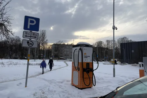 Pilsētas ainava ar stāvvietas zīmi un automa&scaron;īnu sniegā.