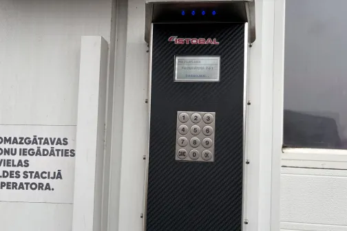 Panelis ar skārienjutīgu ekrānu un pogām pie automazgātuves sienas.