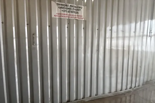 Metāla siena ar uzrakstu, mitra grīda.