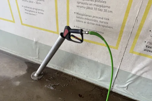 Mazgā&scaron;anas pistole ar zaļu &scaron;ļūteni statīvā JT Carwash automazgātavā Gustava Zemgala gatvē, Rīgā