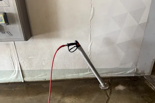 Mazgā&scaron;anas pistole ar sarkanu &scaron;ļūteni statīvā JT Carwash automazgātavā Rīgā