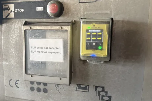 Maksājumu panelis ar kar&scaron;u termināli un uzlīmi par nepieņemtām monētām JT Carwash automazgātavā Rīgā