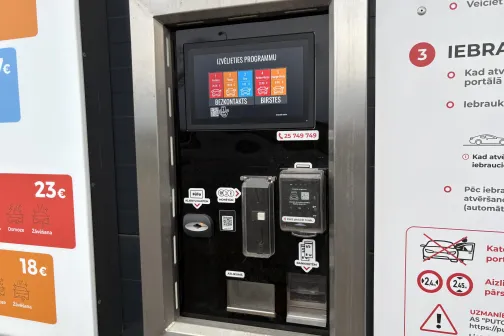 Maksājumu terminālis ar ekrānu &ldquo;Izvēlieties programmu&rdquo; un kar&scaron;u lasītāju PUTO express automazgātavā Rīgā