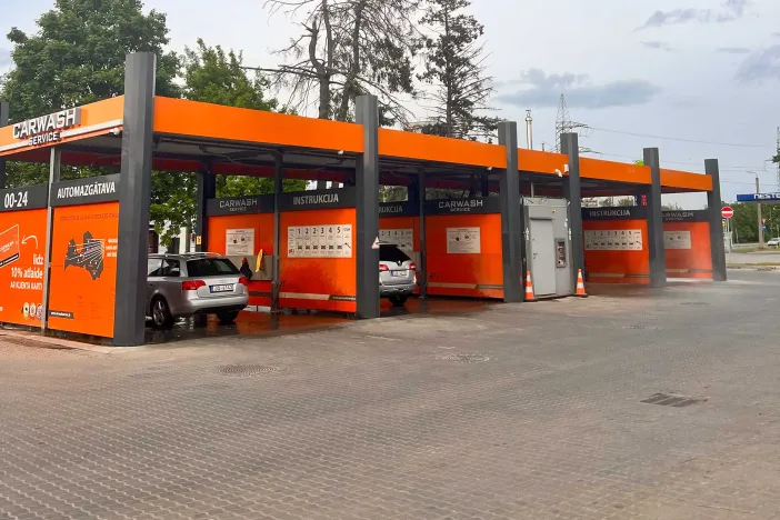 Automa&scaron;īnu mazgātuve ar oranži pelēku dizainu, vairākas automa&scaron;īnas rindā.