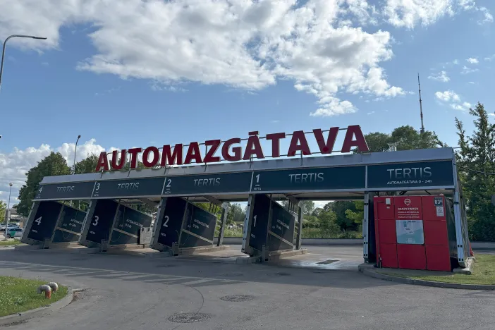 Automa&scaron;īnu mazgātava ar četriem stendiem zem zilām debesīm.