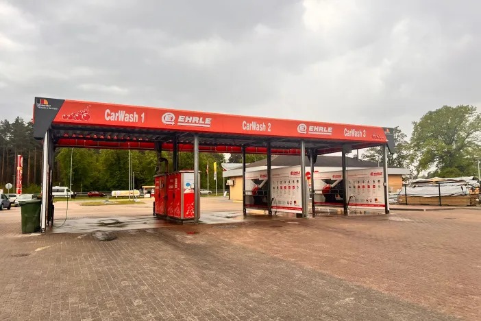 Automa&scaron;īnu mazgātuve ar sarkanu jumtu ārpusē, fonā koki.