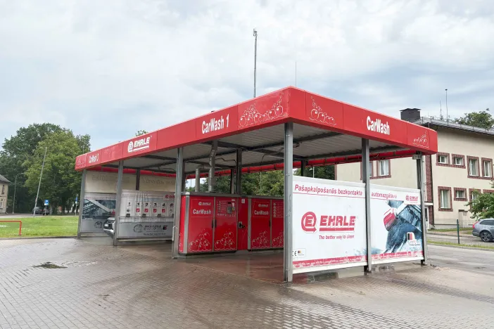 Pa&scaron;apkalpo&scaron;anās automazgātava ar sarkanu jumtu un reklāmas zīmēm.