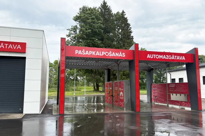 Pa&scaron;apkalpo&scaron;anās automazgātava sarkanā krāsā, blakus balta ēka.