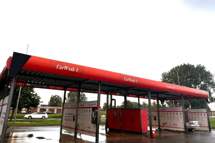 Sarkanās un pelēkās nokrāsās automazgātava ar vairākām stacijām.